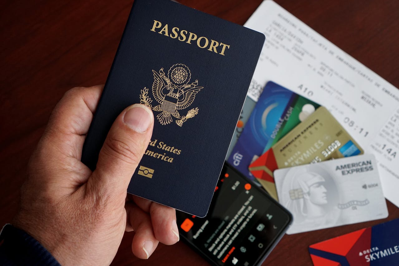 A close-up of a US passport with credit cards, tickets, and a mobile phone on a table.